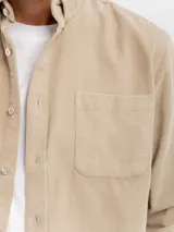 Camisa de manga larga confeccionada en pana de algodón, con cuello clásico, cierre frontal de botones y bolsillo en el pecho.