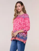 Remera evasé de manga tres cuartos y escote bote, confeccionada en rayón elastizado de color rosado con textura flameada y estampado floral en tonos fucsia y azul.
