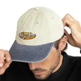 Gorra de béisbol con corona en color beige y visera en color gris. Presenta un logo bordado con la palabra 'Rhythm' sobre un fondo ovalado en el frente.