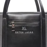 Cartera shopper grande de lona gris con detalles en cuero sintético negro, doble asa de mano y correa ajustable extraíble. Cuenta con un bolsillo frontal externo con cierre y el logo de la marca impreso en plateado.