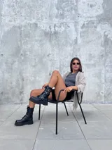 Bota de caña media confeccionada en cuero sintético de alta calidad, con diseño de estilo militar que incorpora cintas decorativas con hebillas metálicas, plataforma y taco cuadrado.