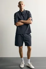 Bermuda estilo jogger de ajuste relajado, confeccionada en tejido interlock de algodón. Cuenta con cintura elástica ajustable con cordón, bolsillos frontales de vivo y diseño liso.