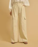 Pantalón acampanado color beige con pinzas, bolsillos italianos y bolsillos de parche con solapas en los laterales. Cierre con botones y cintura con trabillas.