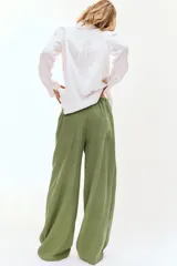 Pantalón de tiro alto con pernera ancha, confeccionado en tejido de lino. Presenta cintura elástica con cordón ajustable, pinzas delanteras, bolsillos laterales y bolsillos de plastrón en la parte posterior.