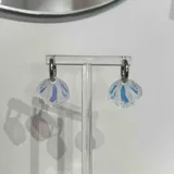 Aros colgantes con forma de concha marina, con base celeste y detalles de hilo blanco.