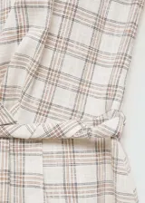 Vestido midi de algodón con estampado de cuadros en tonos neutros. Presenta cuello redondo, diseño sin mangas, corte evasé y detalle de lazo trenzado en la cintura.