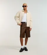 Bermuda baggy de poliuretano color marrón, con diseño amplio y efecto gastado, cintura con trabillas, bolsillos delanteros y traseros.