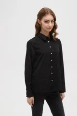 Camisa de poliéster color crema con estampado de pequeños puntos negros, cuello clásico, cierre frontal con botones y mangas largas con puños abotonados.