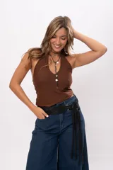Faja de cuero gamuzado con acabado metalizado, color negro, con diseño curvo y flecos largos que se atan en un nudo. Incluye herrajes metálicos plateados.