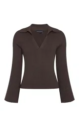 Sweater de punto color marrón, con cuello polo, escote en V profundo y mangas largas con puños acampanados. Presenta un diseño de tejido acanalado vertical.