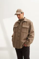 Camisa estilo leñadora marrón con diseño de espiga, cuello clásico, abrochadura frontal a la vista, bolsillos plaqué con tapa en el pecho, mangas largas con puño y botón.