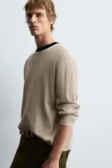 Jersey de manga larga, cuello redondo y calce relajado, color negro con efecto lavado y textura tejida.