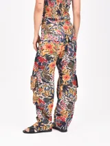 Pantalón cargo de tiro alto con estampado floral y animal print en tonos cálidos y oscuros. Presenta bolsillos cargo voluminosos en los laterales y puños anchos doblados.