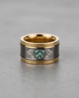 Anillo ancho de acero con banda central oscura, bordes con baño de oro, engastado con una circonia en forma de corazón de color celeste y detalles de pequeñas piedras brillantes.