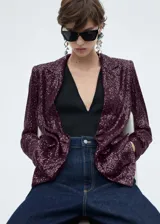 Chaqueta de corte recto con diseño de lentejuelas en color bordó, cuello con solapa, cierre frontal de un botón, manga larga y dos bolsillos delanteros con solapa.
