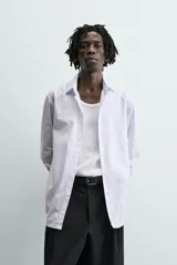 Camisa slim fit blanca con rayas verticales finas en color gris, confeccionada en tejido de algodón. Presenta cuello italiano y manga larga con puño abotonado. Cierre frontal con botonadura.