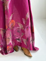 Vestido largo magenta con estampado floral en la parte inferior, de corte holgado y manga larga.