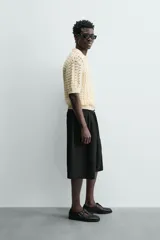 Bermuda negra de corte ancho (wide fit) con pliegues frontales, bolsillos laterales y bolsillos traseros de vivo.