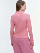 Campera deportiva de cuello alto con cierre frontal de doble cursor. Presenta un corte ajustado que realza la silueta, bolsillos laterales con cierre y mangas largas con puños con abertura para el pulgar.