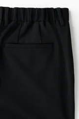 Pantalón sastrero negro de corte slim fit, con presillas para cinto, bolsillos laterales al bies y bolsillos traseros ojalados.