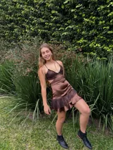 Vestido corto de tela metalizada en tono fucsia con reflejos dorados, con escote en V, diseño de top con triángulos, aberturas laterales en la cintura y doble volado irregular en el ruedo.