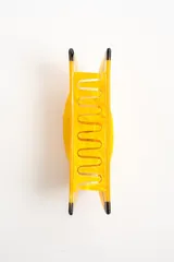 Broche para el pelo en forma de banana, color amarillo con detalles en negro, fabricado en acetato.