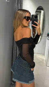 Body negro de manga larga con diseño off-shoulder. El cuerpo presenta una base de tul con lentejuelas brillantes, mientras que las mangas son de tul transparente.