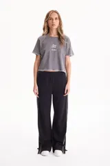 Pantalón deportivo negro de corte wide leg, sin frisa, con ribete blanco en los laterales y aberturas con botones en los tobillos.