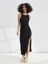 Vestido midi negro sin mangas, de corte ajustado con frunces laterales y abertura alta en la pierna.
