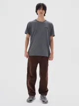 Pantalón cargo de tela tipo brim, color marrón oscuro, con costuras contrastantes en hilo amarillo. Presenta un calce holgado (baggy fit) y detalles de bolsillos cargo.