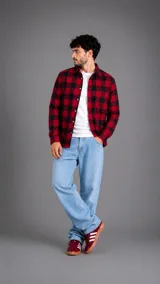 Camisa de manga larga con estampado de cuadros en tonos rojo y negro, confeccionada en tela tipo franela, con cierre frontal de botones y cuello clásico.