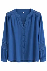 Blusa azul de manga larga con escote en V y cuello mao. Presenta detalles de encaje bordado en los hombros y en las mangas, con cierre frontal de botones y puños ajustados.