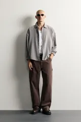 Pantalón jeans de corte relaxed fit, color celeste con efecto lavado, de estilo carpintero con bolsillos laterales y presillas de herramientas.
