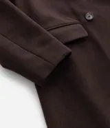 Sobretodo de corte largo y estructura encorpada, color marrón chocolate. Presenta cuello con solapa, cierre frontal de doble abotonadura y bolsillos laterales con solapa.