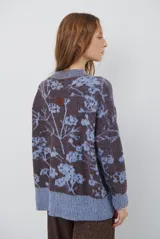 Buzo de tejido de punto con cuello redondo, mangas largas con puños acanalados y diseño estampado de flores en tonos rojos.
