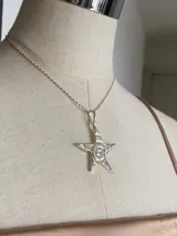 Collar de plata con cadena fina y dije colgante con forma de estrella de cinco puntas, con un espiral grabado en el centro.