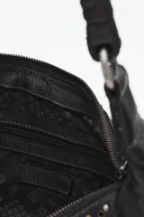 Cartera de cuero vacuno negra, estilo media luna o hobo, con asa de hombro trenzada. Presenta paneles laterales decorados con tachas metálicas doradas y plateadas. Cuenta con bolsillos externos con cierre en los laterales.