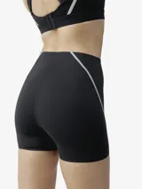 Short deportivo negro de tejido Shape_Tech, con tecnología performance, compacto y ligero. Diseño sin cinturilla, con costuras termoselladas y cinta reflectante decorativa en los laterales.
