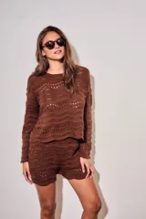 Short tejido de punto con diseño de ondas y calados, color blanco. Presenta cintura elástica acanalada y corte mini.