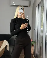 Sweater de tejido de punto con diseño de trenzas verticales, cuello redondo y mangas largas con puños ajustados que presentan detalle de botones metálicos.