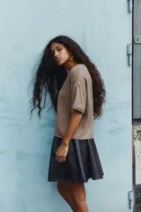 Buzo de punto suave color marrón, de corte holgado, con cuello redondo acanalado, hombros caídos y mangas cortas.