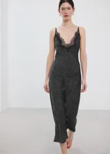 Vestido midi de estilo lencero color negro con estampado de lunares blancos, escote en V con detalle de encaje negro, tirantes finos y diseño entallado.