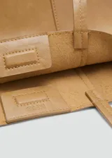 Bolso tipo shopper de tamaño mediano, confeccionado en poliuretano con acabado liso y brillante. Cuenta con dos asas de hombro, cierre de botón magnético y forro interior de piel.