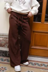 Pantalón tejido de punto color beige, de corte holgado y perneras anchas, con cintura elástica y cordón ajustable.