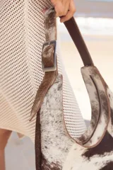 Cartera negra de cuero con forma de medialuna y tachas en zigzag.