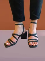 Sandalias de tacón alto color blanco, con tiras trenzadas y cierre con hebilla en el tobillo.