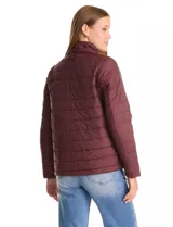 Campera 3 en 1 de color beige, con sistema de capas desmontables. La capa exterior es de tejido técnico resistente al viento y lluvia ligera, con capucha fija, cierre frontal con solapa, bolsillos de parche y ajuste elástico interno en la cintura. Incluye una campera interior capitoneada ultraliviana que puede usarse de forma independiente.