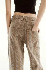 Pantalón de tiro medio en color marrón con diseño de animal print y aplicaciones de brillos en contraste. Cuenta con cinco bolsillos, presillas para cinturón y cierre frontal con cremallera y botón metálico.