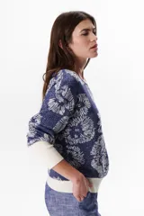 Sweater de tejido de punto con diseño floral, confeccionado en una mezcla de algodón y lurex. Presenta cuello redondo, mangas largas con puños anchos en color crema y un calce holgado.