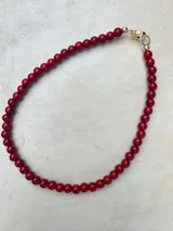 Collar de cuentas esféricas de vidrio pulido en color rojo intenso, con cierre metálico bañado en oro 18k.